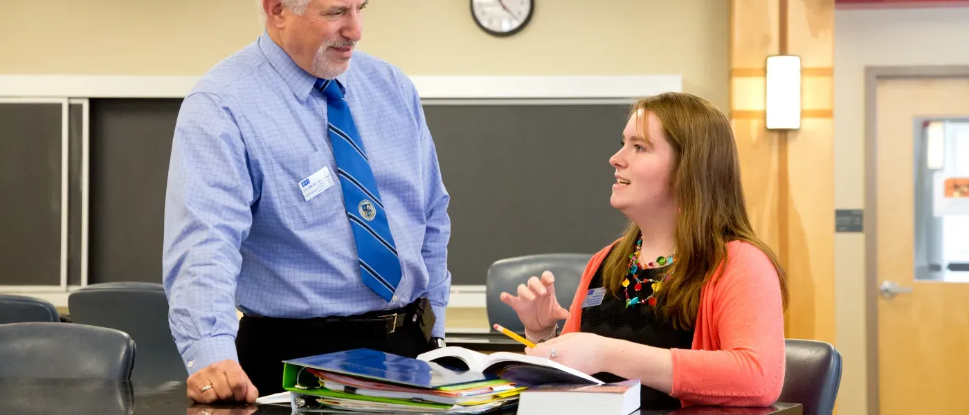 U N E College of Pharmacy student studies in a classroom with professor